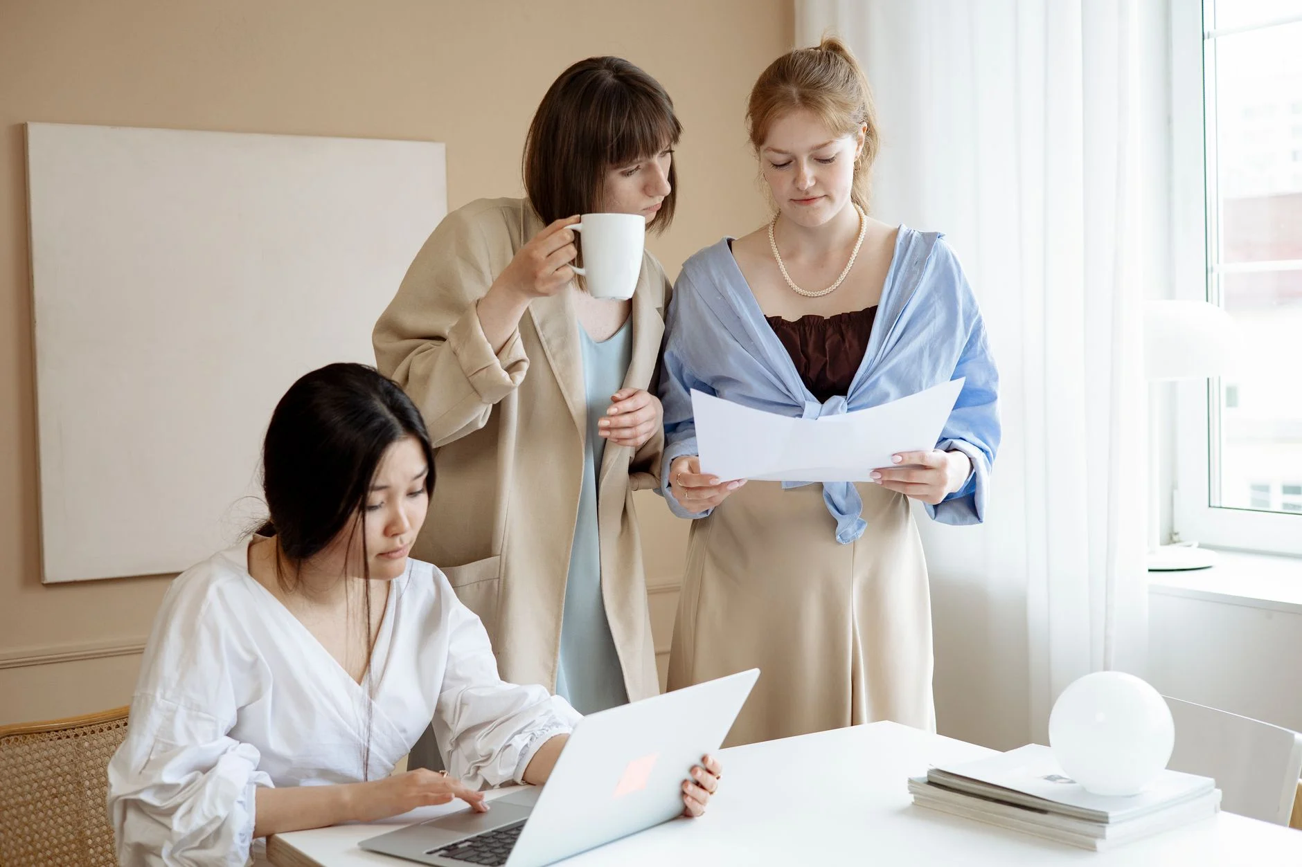 Nhóm đồng nghiệp cùng đọc tài liệu bên máy tính